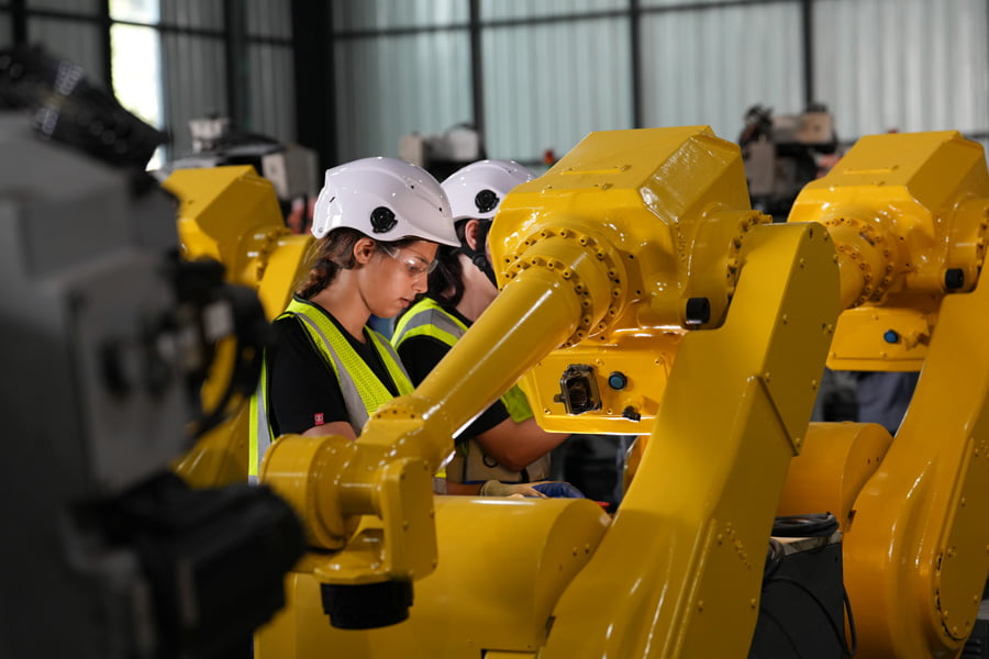 Robotics engineer working on maintenance of robotic arm in factory warehouse